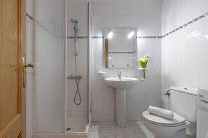 Un bagno con doccia, lavandino, water e porta in legno.