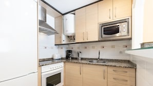A compact kitchen with a built-in stove, oven, microwave, and a water heater. - CARLOS V Apartment (Salou)