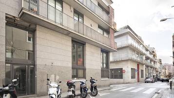 Un edificio moderno con ingresso a livello strada, un'area di parcheggio e diversi scooter parcheggiati.