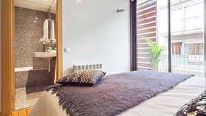 Une chambre moderne avec un grand lit, une salle de bain avec douche et lavabo, et un balcon avec vue.
