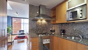 Une cuisine moderne dotée de plans de travail en granit, d’appareils électroménagers en acier inoxydable et d’armoires en bois.