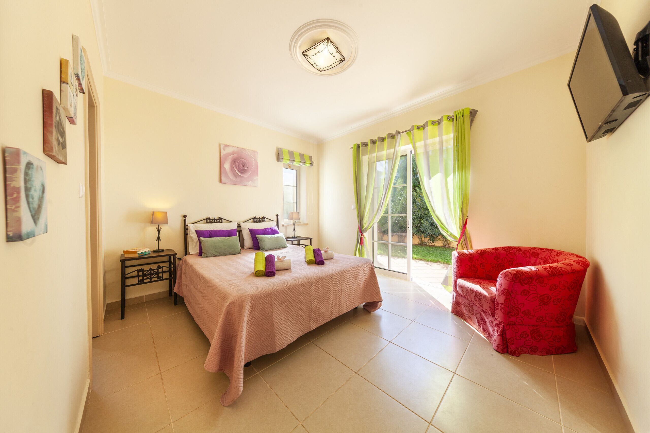Une chambre à coucher avec un lit, une table de chevet, une lampe et une chaise rouge.