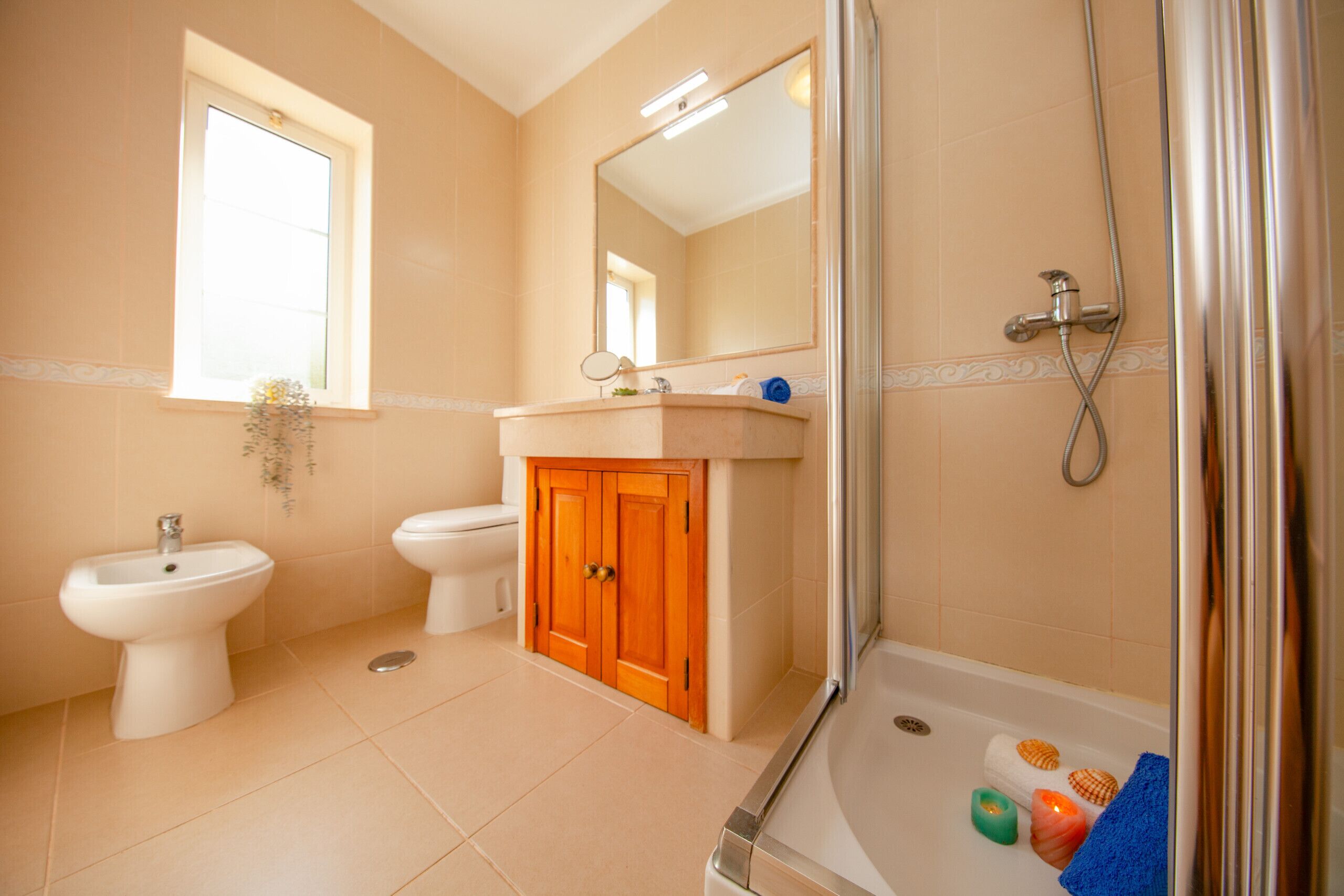 A bathroom with a shower, bidet, toilet, and vanity.