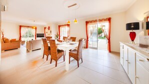 A spacious living area with a dining table, wicker chairs, and a sofa. - Villa w/ private pool & BBQ in Varandas do Lago (Almancil)
