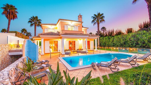 A two-story house with a swimming pool, lounge chairs, and palm trees. - Villa w/ private pool & BBQ in Varandas do Lago (Almancil)