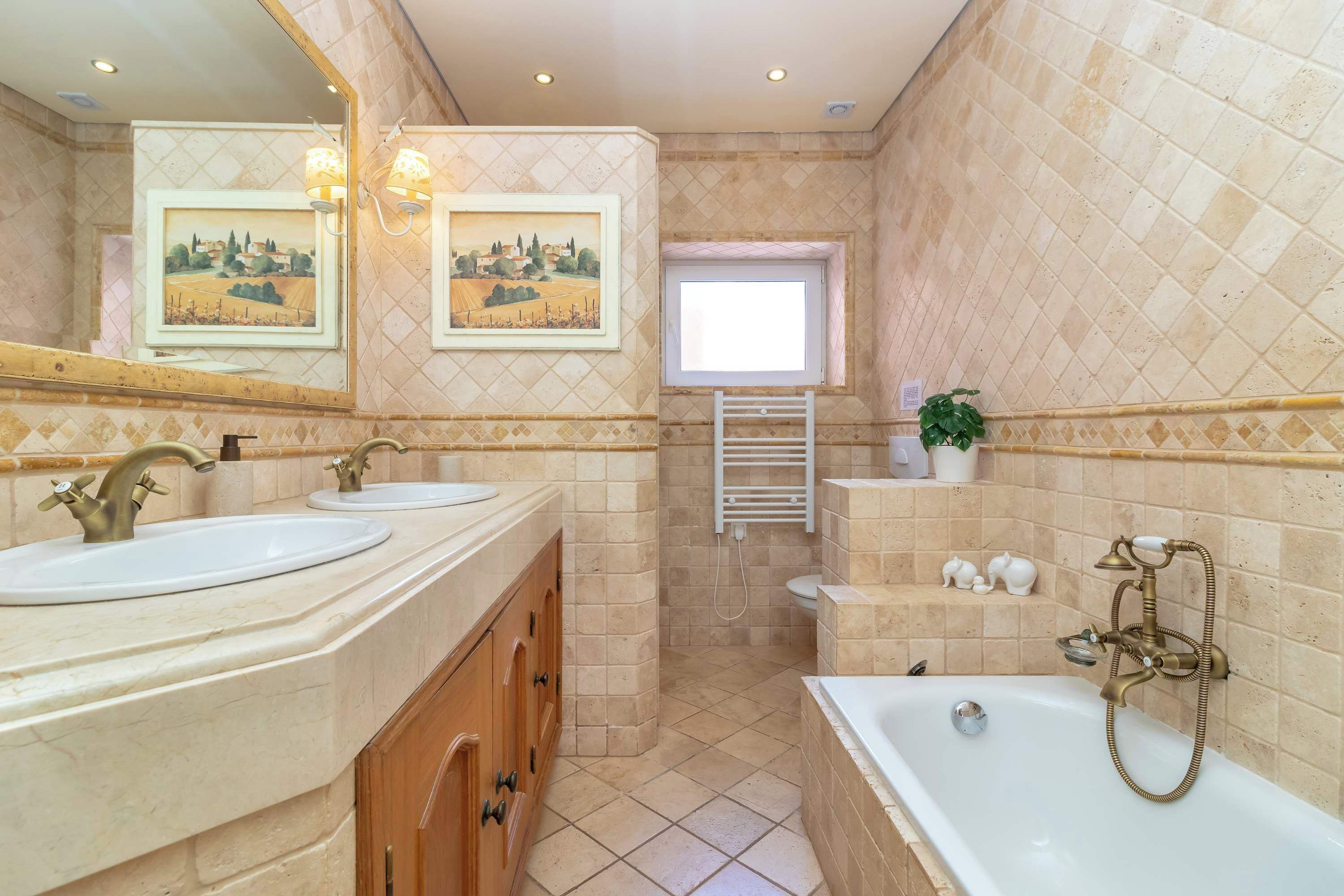 Une salle de bain avec deux lavabos, une baignoire, une fenêtre et un porte-serviettes.