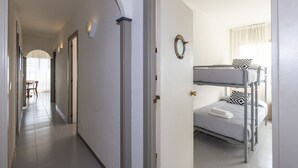 A hotel room with a bunk bed, a small table, and a chair in the hallway. - GOLF SANT JORDI 2 Apartment (Cambrils)