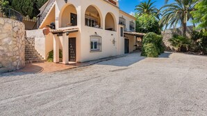 Un edificio de dos pisos con una escalera de piedra que conduce a la entrada, un patio cubierto y un camino de entrada de grava.