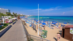 A beach with sun loungers and umbrellas, a boardwalk, and a lifeguard tower. - Villa Marizan - Private Pool Retreat (Protaras)