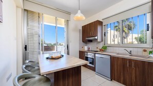 A modern kitchen with a central island, wooden cabinets, a built-in oven, and a dishwasher. - Villa Marizan - Private Pool Retreat (Protaras)