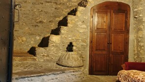 A rustic room with stone walls, a wooden door, and a bed with a patterned bedspread. - stone cottage, Medieval Village. 15 km Sea. Terrace (Castelvecchio di Rocca Barbena)