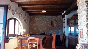 A rustic interior with a stone wall, wooden ceiling beams, and a dining area with wooden furniture. - stone cottage, Medieval Village. 15 km Sea. Terrace (Castelvecchio di Rocca Barbena)