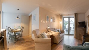 A spacious living room with a sofa, armchairs, and a dining area with a table and chairs. - 2-bedroom dog friendly cottage located in Braunton, within easy reach of the beach. (Braunton)