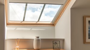 A skylight with a view of the sky, a wooden shelf with a vase and a picture frame, and a small table. - 2-bedroom dog friendly cottage located in Braunton, within easy reach of the beach. (Braunton)