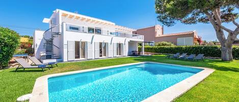 A modern two-story house with a swimming pool, a covered outdoor area, and a well-maintained lawn.