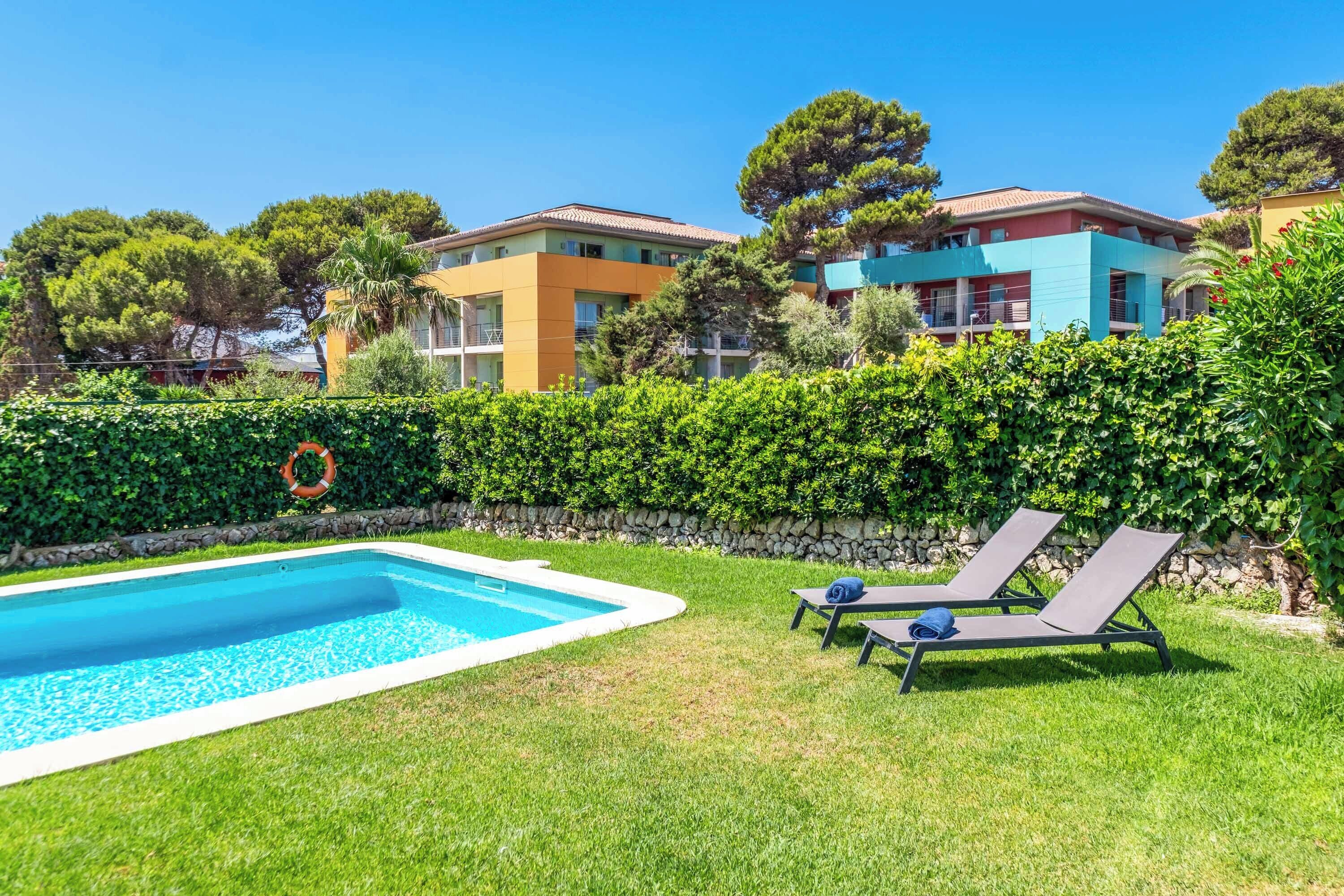 Ein Pool mit Liegestühlen, eine Steinmauer und eine Hecke.
