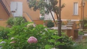 A garden with hydrangea flowers, a lamp post, and a building with a staircase. - Domus Costanza - Bright and elegant apartment in Piazza Verbano. (Roma)