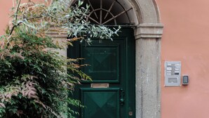 A green door with a number '32' above it, a potted plant to the left, and a metal doorbell on the wall. - Lovely Trastevere - An Authentic Experience .. (Roma)
