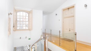 A modern interior with a staircase, glass railing, a wooden floor, and a door. - Chiado | CHARMING & ROMANTIC | Family-Friendly (Lisboa)