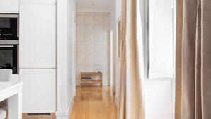 A modern kitchen with white cabinetry, a built-in oven, and a wooden bench. - Chiado | CHARMING & ROMANTIC | Family-Friendly (Lisboa)