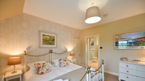 A neatly arranged bedroom with a bed, bedside tables, a dresser, and a mirror.