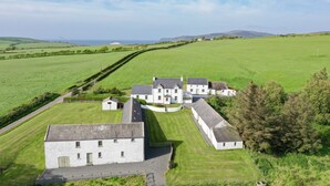 A large estate with multiple buildings, a well-maintained lawn, and a view of the sea.