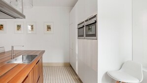 A modern kitchen with a wooden countertop, stainless steel sink, and double ovens. - Palazzina Canal Apartment (Venezia)