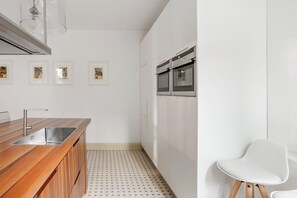 A modern kitchen with a wooden countertop, stainless steel sink, and double ovens. - Palazzina Canal Apartment (Venezia)