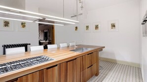 A modern kitchen with a wooden countertop, stainless steel sink, and a built-in gas stove. - Palazzina Canal Apartment (Venezia)
