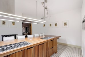 A modern kitchen with a wooden countertop, stainless steel sink, and a built-in gas stove. - Palazzina Canal Apartment (Venezia)