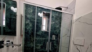 Une salle de bain moderne avec une douche à parois de verre, un grand lavabo blanc et des toilettes.