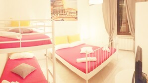 Une chambre avec des lits superposés, une fenêtre avec des rideaux, un radiateur et un téléviseur.