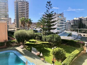 A residential area with a swimming pool, lush greenery, and modern buildings in the background. - ALBAIDA BLUELINE R015 (Benidorm)