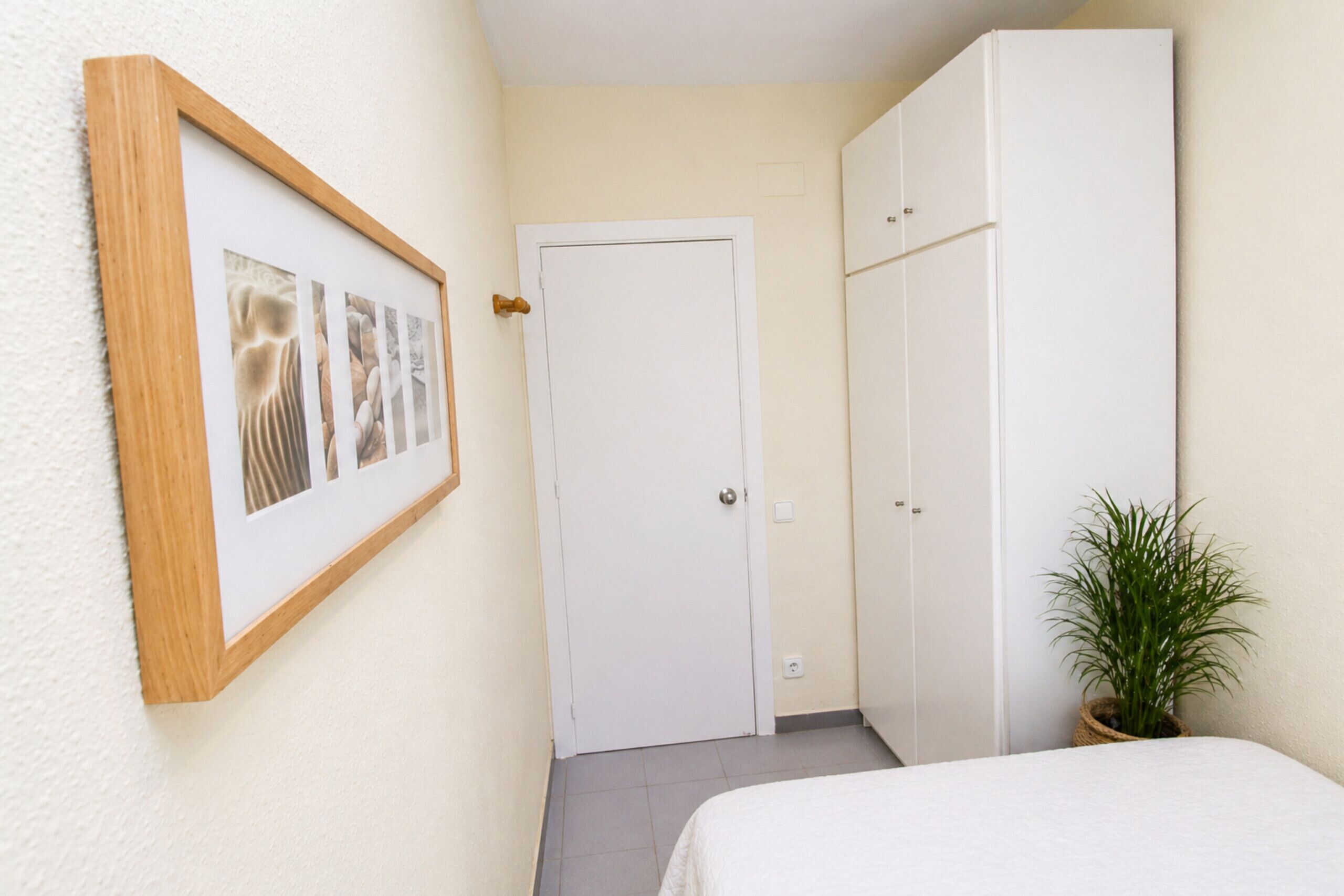 Une chambre à coucher avec un lit, une armoire, une porte et un tableau encadré au mur.