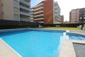 A swimming pool with a clear blue water surface, surrounded by a concrete deck. - ROURA Apartment - Beach 100m (La Pineda)