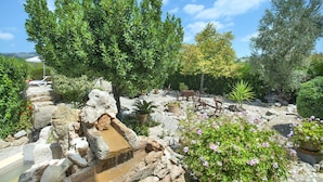 A garden with various plants, a stone structure, and outdoor furniture.