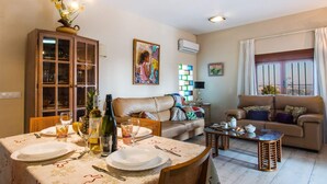A living room with a dining table set for four, a sofa, a coffee table, and a cabinet with glass doors.