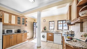 A modern kitchen with wooden cabinets, a microwave, a washing machine, and a sink.