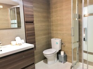 A modern bathroom with a white sink, a toilet, and a glass shower enclosure.