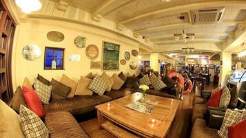 A cozy living area with a wooden coffee table, a sofa with plaid cushions, and a wall adorned with various decorative plates and a painting.