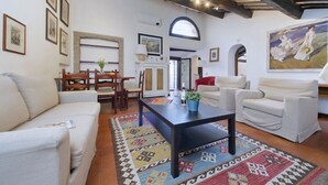 Un salon spacieux avec une cheminée, des canapés blancs, une table basse et un tapis à motifs.