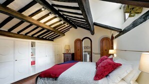 Une chambre à coucher avec un lit, une armoire blanche et un plafond avec des poutres apparentes.