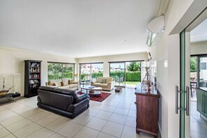 A spacious living room with a leather sofa, a bookshelf, and a coffee table.