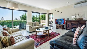 Un salón amplio con un ventanal grande, un sofá, una mesa de centro y un televisor.