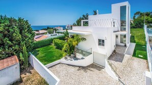 Un moderno edificio blanco con un patio empedrado, un balcón de cristal y vistas al mar.