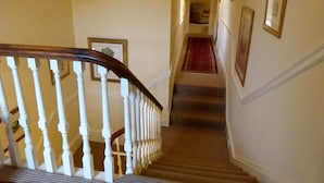 Eine Treppe mit weißen Balustraden und einem hölzernen Geländer, das zu einer Zwischenebene führt.
