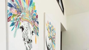 A wall with multiple artworks featuring stylized animal heads.