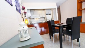 Un coin repas avec une table et des chaises, une cuisine en arrière-plan et une lanterne décorative posée sur le comptoir.