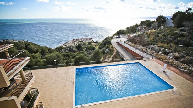 Une piscine avec vue sur la mer et sur une route.
