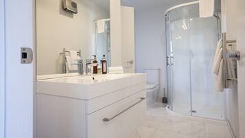 A modern bathroom with a white vanity, a glass shower enclosure, and a toilet.